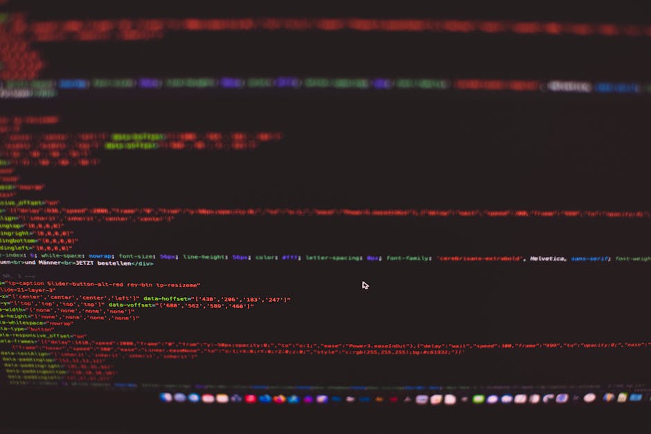 A close-up view of a laptop computer displaying a screen filled with lines of code and programming scripts. The laptop is situated in a dimly lit environment, with a faint blue and pink glow reflectin